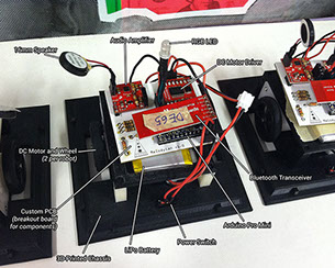 Internal electronics of a Musical Melodyian robot: Arduino, motor driver, two wheeled DC motors, RGB LED, audio amp, speaker, and battery.