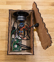 Interior view of Sonic Mirror (v2) enclosure containing Raspberry Pi 3, speaker, amplifier, wires, and other electronic components.